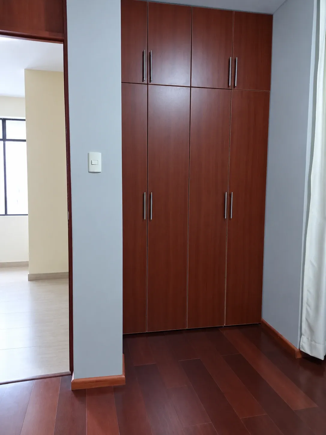 Clóset empotrado con acabado madera, cuatro puertas abatibles cerradas, compartimentos superiores y tiradores metálicos.